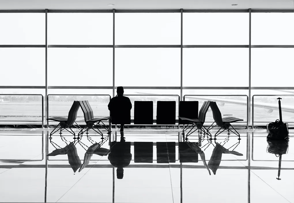 Silhouette of a person waiting at an airport, symbolizing travel to Brisbane for eye surgery.