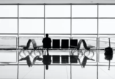 Silhouette of a person waiting at an airport, symbolizing travel to Brisbane for eye surgery.