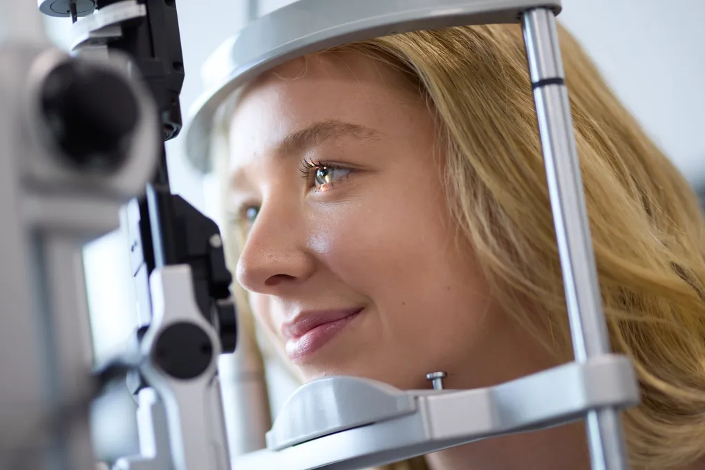 Young woman undergoing an eye examination with a slit lamp, preparing for laser eye surgery consultation in Brisbane.