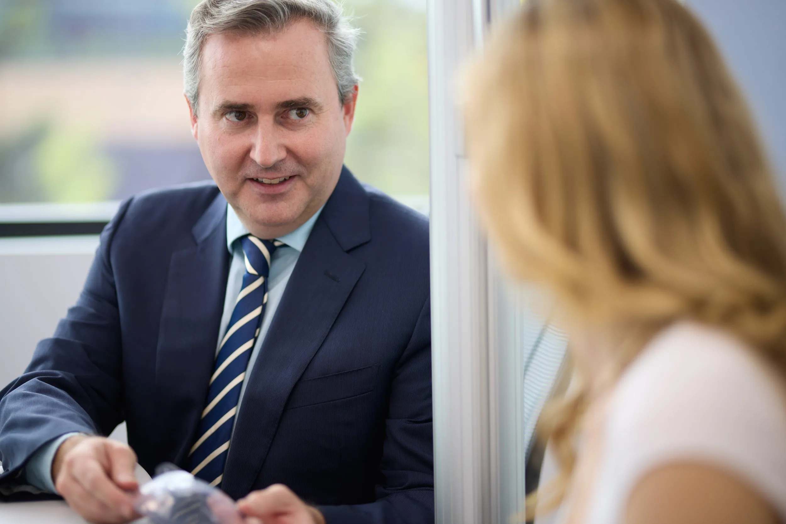 A friendly Brisbane ophthalmologist in a suit smiles while discussing cataract surgery options with a patient.