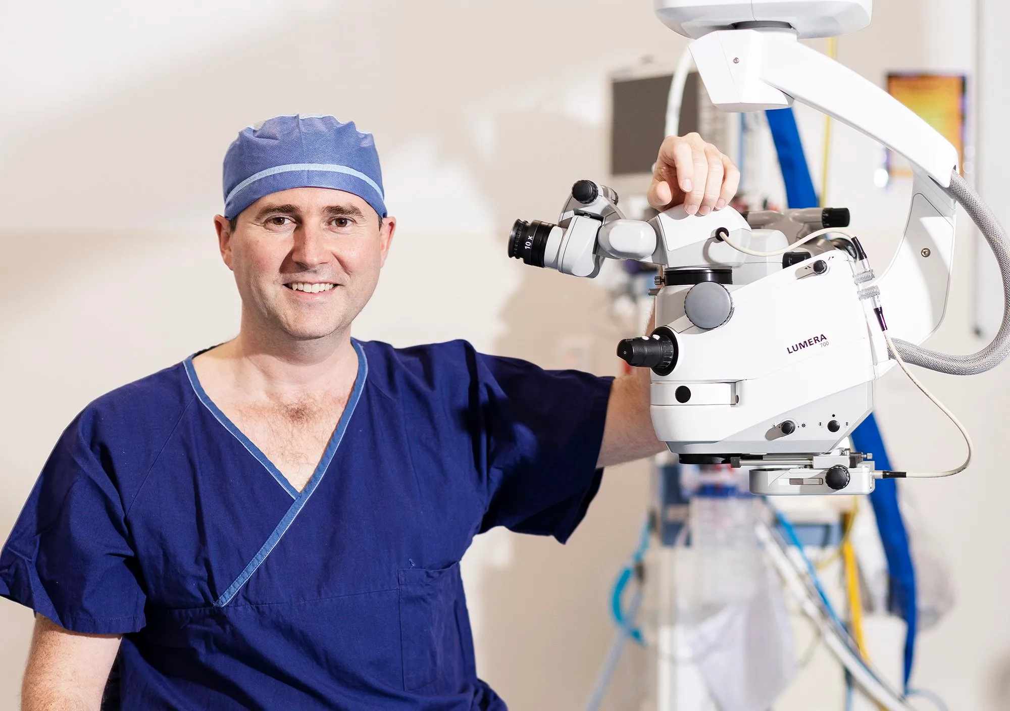 Smiling ophthalmic surgeon adjusts a Lumera 700 surgical microscope, essential for precision in eye surgery procedures.